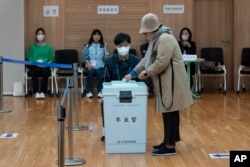 Seorang ibu memberikan suaranya dalam pemilihan parlemen di sebuah tempat pemungutan suara di Seoul, Korea Selatan, Rabu, 10 April 2024. (Foto: AP)