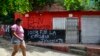 Una mujer pasa frente a una casa con un grafiti del grupo guerrillero ELN, cerca del restaurante donde dos policías metropolitanos de Cúcuta fueron asesinados en la mañana, en el municipio de El Zulia, cerca de Cúcuta, Colombia, el 4 de julio de 2023