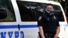 Un agente de la policía de Nueva York usa un tapabocas con líneas azules que indican su apoyo a las fuerzas del orden en la escena de un tiroteo en Brooklyn, Nueva York, e 25 de junio de 2020.