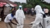 FILE - Health workers wash after drawing a blood specimen from a child suspected of being exposed to a teenager who'd died of the Ebola virus on the outskirts of Monrovia, Liberia, June 30, 2015.