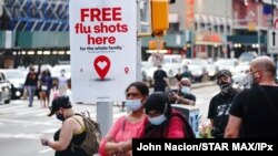 Un anuncio ofrece vacunas gratuitas contra la gripe mientras gente camina durante una protesta en Brooklyn, Nueva Yor, el 21 de agosto de 2020.