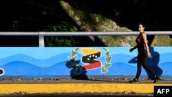 Una mujer pasa junto a un mural de la campaña electoral de Freddy Bernal, candidato a gobernador del Táchira por el partido gobernante Amemos al Táchira, en San Cristóbal, Venezuela, el 11 de noviembre de 2021.