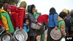 FILE - Syrian children queue to receive food distributed by humanitarian aid workers at a makeshift camp for displaced people, near the village of Yazi Bagh, Feb. 7, 2018. 