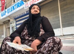 Soufida Gedou, 65, a Syrian refugee living in Akcakale, Turkey, waits for bread distribution by the local municipality, holds various identification documents, Oct. 20, 2019.