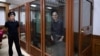 US journalist Evan Gershkovich, accused of espionage, smiles from inside a glass defendants' cage prior to a hearing in Yekaterinburg's Sverdlovsk Regional Court on June 26, 2024. (Photo by NATALIA KOLESNIKOVA / AFP)