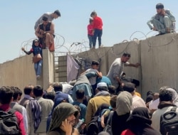 Un hombre lanza a una niña para entrar al aeropuerto internacional Hamid Karzai de Kabul, el lunes 16 de agosto de 2021.
