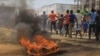 Protesters walk past a burning tyre in the Eastern Congolese town of Beni, Friday Dec. 28, 2018, as they demonstrate against the election postponed until March 2019, announced by Congo's electoral commission for Beni residents that is blamed on a deadly Ebola outbreak. 