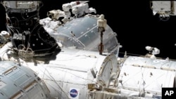 En esta imagen tomada del video de la NASA, los astronautas de la NASA Mike Hopkins, al centro a la derecha, y Victor Glover, al centro a la izquierda, trabajan fuera del laboratorio de la Estación Espacial Internacional, el miércoles 27 de enero de 2021.