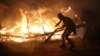 A migrant is seen in silhouette near flames from a burning makeshift shelter on the second day of the evacuation of migrants and their transfer to reception centers in France, as part of the dismantlement of the camp called the "Jungle" in Calais, France, Oct. 25, 2016.