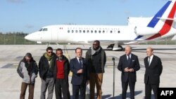 French president Francois Hollande (4thL) flanked by former French hostages, French Foreign Minister Laurent Fabius and Defense Minister Jean-Yves Le Drian upon the hostages' arrival at the military airport of Villacoublay outside Paris, Oct. 30, 2013.