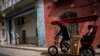 Con máscara en medio de la pandemia de COVID-19, un hombre transporta a un cliente en un taxi-bicicleta en La Habana, Cuba, el miércoles 16 de febrero de 2022.