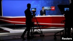 FILE - A news anchor is seen on camera during a broadcast at Tolo News studio, in Kabul, Afghanistan, Oct. 18, 2015.