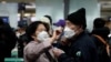 A woman wearing a mask to prevent contracting the coronavirus adjusts her husband's mask as they wait to check in at Incheon International Airport in Incheon, South Korea, March 19, 2020.
