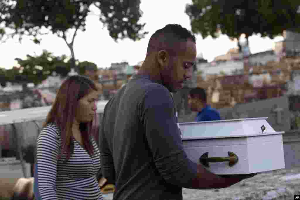នាងClaudineia dos Santos Melo និងKlebson Cosme da Silva កាន់ម្ឈូសកូនប្រុសរបស់ខ្លួនឈ្មោះ Arthur Cosme នៅពេលដែលពួកគេបូជាកូននៅទីបញ្ចុះសពមួយក្នុងទីក្រុង Rio de Janeiro ប្រទេសប្រេស៊ីលកាលពីថ្ងៃទី៣១ កក្កដា ២០១៧។ ក្មេងនោះត្រូវបានបាញ់ស្លាប់តាំងពីក្នុងពោះម្តាយកាលពីមួយខែមុន វាបង្ហាញថាពីហិង្សាដែលកំពុងកើនឡើងក្នុងតំបន់អនាធិបតេយ្យក្នុងទីក្រុង។