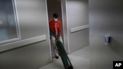 Un trabajador de la salud arrastra un tanque de oxígeno en el hospital Ana Francisca Pérez de León II en Caracas, el 23 de marzo de 2021.