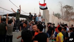 Protesters raise the Iraqi flag at the gate of the Iranian consulate building before storming and burning it in Basra, 340 miles (550 km) southeast of Baghdad, Iraq, Sept. 7, 2018. 
