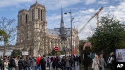 Peatones caminan cerca de la emblemática catedral de Notre Dame de Francia, horas antes de reabrir formalmente sus puertas por primera vez desde que un devastador incendio casi destruyó el monumento de 861 años de antigüedad en 2019, el sábado 7 de diciembre de 2024, en París. 