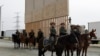 FILE - U.S. Border Patrol officers on horseback watch President Donald Trump (not pictured) review border wall prototypes in San Diego, March 13, 2018.