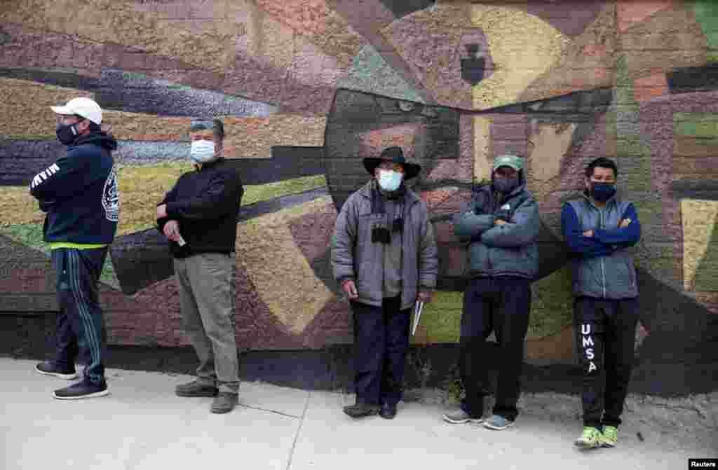 Un grupo de votantes hacen fila, mientras usan m&#225;scaras protectoras, y esperan en un colegio electoral para poder sufragar durante las elecciones presidenciales en La Paz, Bolivia.