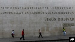 La gente pasa por delante de un mural en piedra con frases de Simón Bolívar cerca de la Asamblea Nacional de Venezuela en Caracas, en enero de 2020.