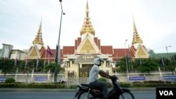 រូបឯកសារ៖ បុរស​ម្នាក់​បរ​ម៉ូតូ​កាត់​មុខ​រដ្ឋ​សភា​ក្នុង​ក្រុង​ភ្នំពេញ កាលពីល្ងាចថ្ងៃទី០២ ខែឧសភា ឆ្នាំ២០១៨។ (អូន ឆេងប៉រ/វីអូអេ)
