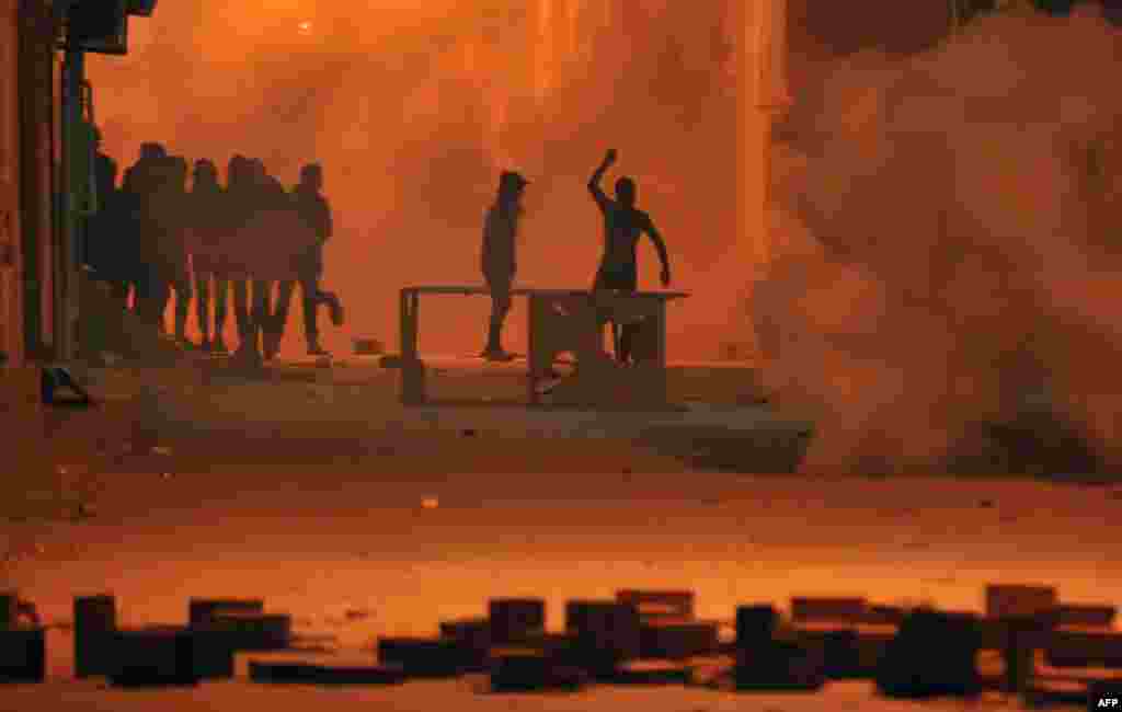 Tunisian protesters throw stones towards security forces in Tunis&#39; Djebel Lahmer district after price hikes ignited protests in the North African country.