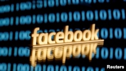 FILE - A 3-D printed Facebook logo is seen in front of displayed binary code in this illustration picture, taken June 18, 2019.