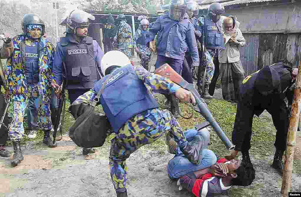 A police officer kicks a protester during a clash after protesters attacked and set fire to polling booths, Bogra, Bangladesh, Jan. 5, 2014.