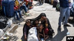 Una mujer cubre a sus hijos con un manto mientras esperan con otros trabajadores migratorios poder inscribirse para abordar un tren a casa. 