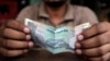 A cashier at an Indian restaurant counts money in New Delhi, India, June 13, 2013. 
