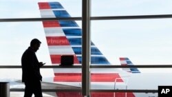 ARCHIVO - Un pasajero habla por teléfono con aviones de American Airlines estacionados detrás de él en el Aeropuerto Nacional Ronald Reagan de Washington, el 25 de enero de 2016. (Foto AP/Susan Walsh)