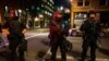Policías de armados con fusiles de guerra mantienen la vigilancia en Portland, Oregon, durante protestas en agosto.