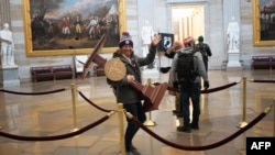 WASHINGTON, DC - JANUARY 06: A pro-Trump protester carries the lectern of U.S. Speaker of the House Nancy Pelosi through the Roturnda of the U.S. Capitol Building after a pro-Trump mob stormed the building on January 06, 2021 in Washington, DC…