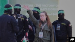 La soldado israelí Agam Berger saluda a la multitud junto a militantes enmascarados de la Jihad Islámica mientras es entregada a la Cruz Roja en el campo de refugiados de Jabalia en la ciudad de Gaza, el 30 de enero de 2025.