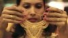 A salesgirl shows a gold necklace to customers at a jewelery showroom in the northern Indian city of Chandigarh, November 11, 2012. 