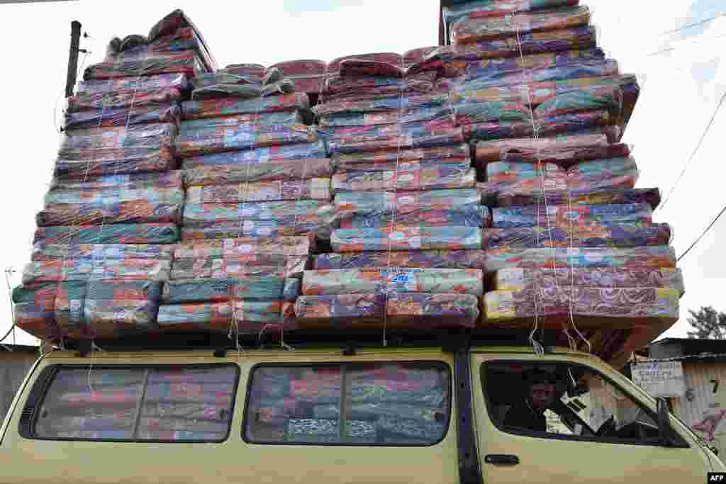 A man transports a pile of mattresses on the roof of a minivan in Ng'ando slum in the Kenyan capital, Nairobi, Jan. 16, 2018.