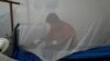 Un joven se sienta detrás de un mosquitero en el Hospital Municipal, mientras recibe tratamiento por dengue, una enfermedad transmitida por mosquitos, en Caranavi, Bolivia, el 2 de marzo de 2023. 