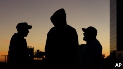 Migrantes salvadoreños hablan mientras se preparan para partir hacia la frontera de EE.UU. con otros en una caravana, en San Salvador, El Salvador, al amanecer del miércoles 16 de enero de 2019. 