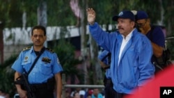 Escoltado por uno de sus guardias de seguridad armados, el presidente nicaragüense Daniel Ortega, derecha, saluda a una multitud de seguidores durante una marcha por la paz, en Managua, Nicaragua, el sábado 7 de julio de 2018. Según grupos de derechos humanos nicaragüenses más de 300 personas han sido asesinadas desde que comenzaron las protestas antigubernamentales hace más de dos meses. (AP Photo / Alfredo Zuniga)