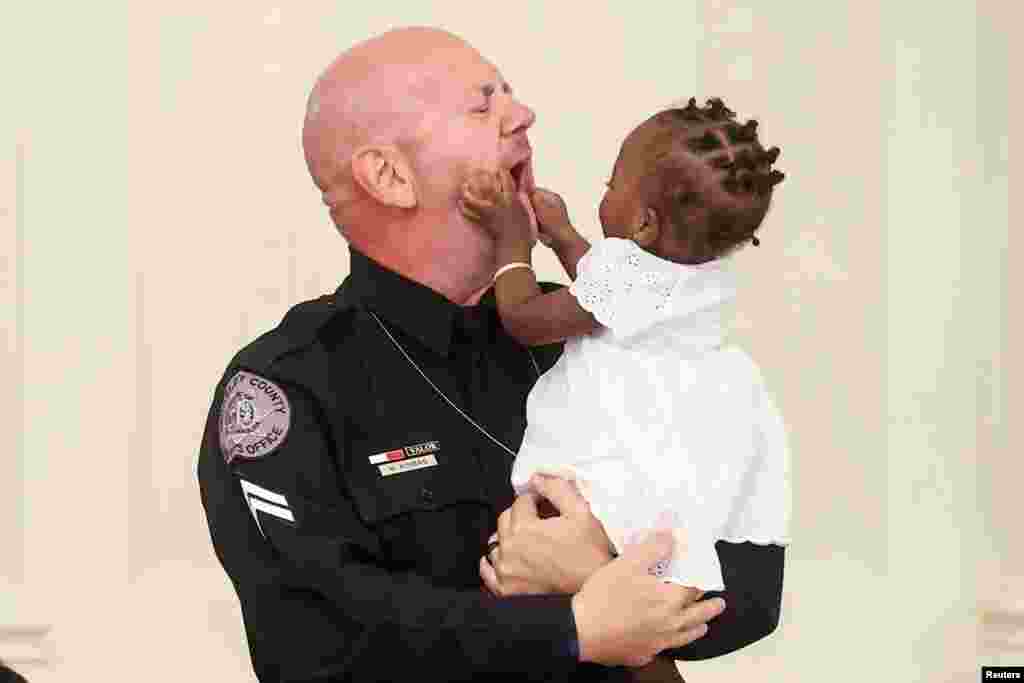 One-year-old Ryleigh Boyd grabs the face of Berekely County Sheriff&#39;s Deputy William Kimbro during a roundtable discussion on law enforcement hosted by U.S. President Donald Trump in the East Room of the White House in Washington, July 13, 2020.&nbsp;Kimbro is credited with saving the life of young Ryleigh during a traffic stop in 2019.