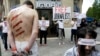 FILE - Reporters Without Borders activists, bound and made up as mock victims, demonstrate outside the Iran Air office on the Champs Elysées in Paris, July 10, 2012, to protest the imprisonment of Iranian journalists.