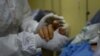 Un trabajador de la salud toma la mano de un paciente con COVID-19 en la unidad de cuidados intensivos del Hospital público Ana Francisca Pérez de León II en Caracas, Venezuela. Marzo 28, 2021.