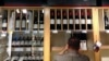 FILE - Bottles of Penfolds Grange, made by Australian wine maker Penfolds and owned by Australia's Treasury Wine Estates, are displayed as a shop assistant places more wine bottles onto shelves below at a wine shop in central Sydney, Australia, Aug. 2014