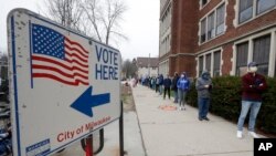 Votantes hacen fila en la escuela secundaria Riverside High School en Milwaukee, Wisconsin, para votar en las primarias demócratas el martes, 7 de abril de 2020.