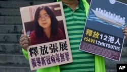 A pro-democracy activist holds placards with the picture of Chinese citizen journalist Zhang Zhan outside the Chinese central government's liaison office, in Hong Kong, Dec. 28, 2020. 