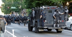 Agentes de policía en Seattle viajan en un vehículo blindado detrás de otros oficiales en bicicleta durante una protesta de Black Lives Matter, el sábado 25 de julio de 2020.