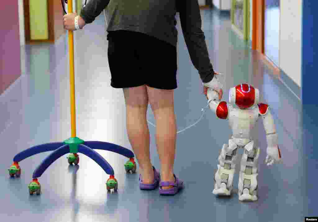 Ian Frejean (11 tahun) berjalan bersama robot manusia &quot;Zora&quot; yang diciptakan untuk menghibur para pasien di rumah sakit kota Ostend, Belgia.
