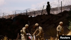 Miembros de la Guardia Nacional de Texas extienden alambradas de púas en cruces de la frontera entre EEUU y México el 13 de mayo de 2023.