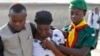 A woman is consoled by church members as she grieves near the graves of victims of a suicide bomb attack during a memorial service at St. Theresa's Church in Madalla, on the outskirts of Abuja, December 23, 2012. 