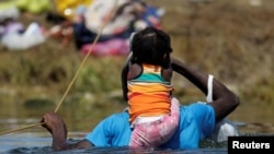 Un migrante con un niño en busca de refugio en EE. UU. atraviesa el Río Bravo desde Ciudad Acuña, México, hacia Del Rio, Texas, EE.UU., el 22 de septiembre de 2021.